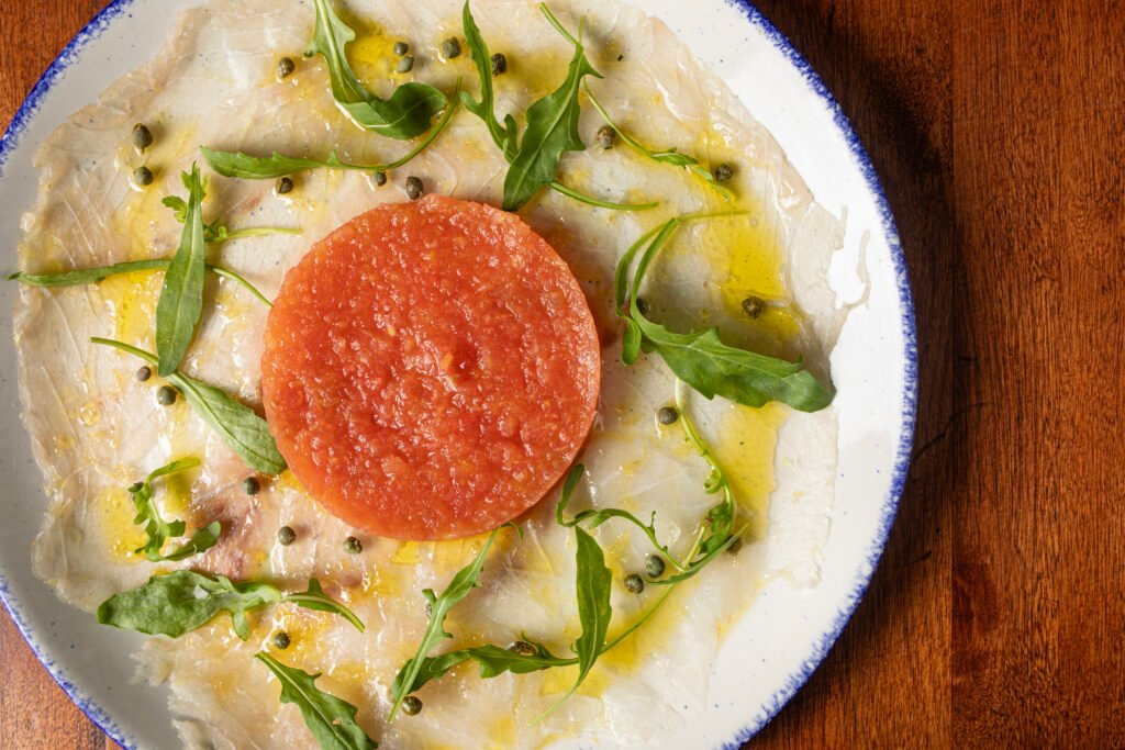 Poisson au Tartare de Tomat, com lâminas de peixe branco, mini alcaparras e tartar de tomate | Foto: Tati Frison