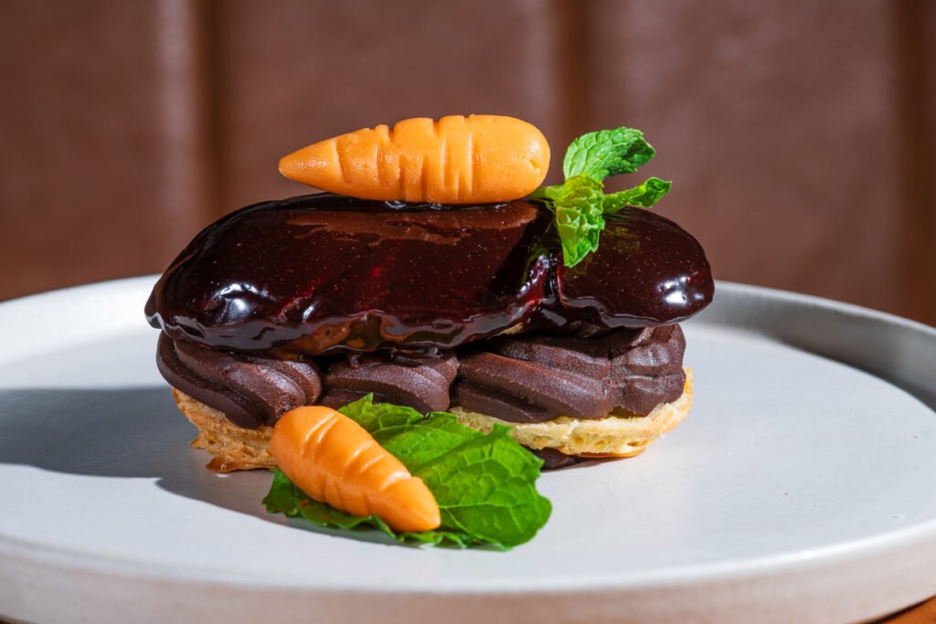 no Francês Rendez Vous a sobremesa homenageia a Páscoa com a Eclair Paques com creme belga de chocolate 70% com pinceladas de creme de cenoura e ganache de chocolate meio amargo | Foto: Gustavo Pitta